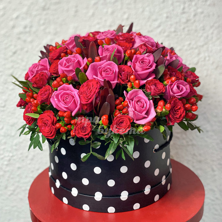 Пурпурные розы с гиперикумом в коробке (на фоне стены)